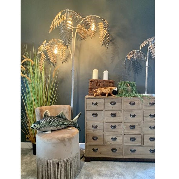 Decorative room setup with palm tree lamp, fish sculpture, and wooden cabinet.