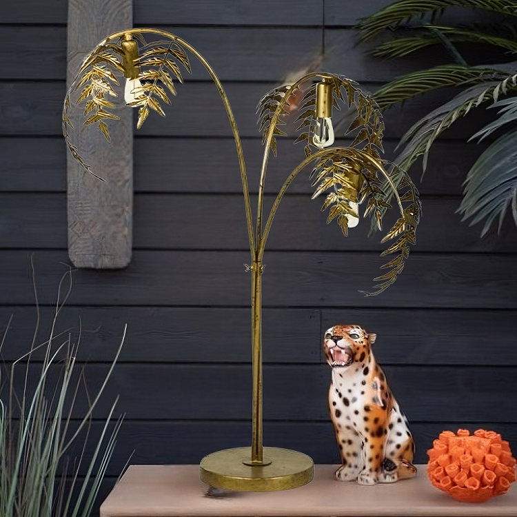 Decorative gold palm tree lamp with a cheetah figurine and orange ball on a dark wooden background